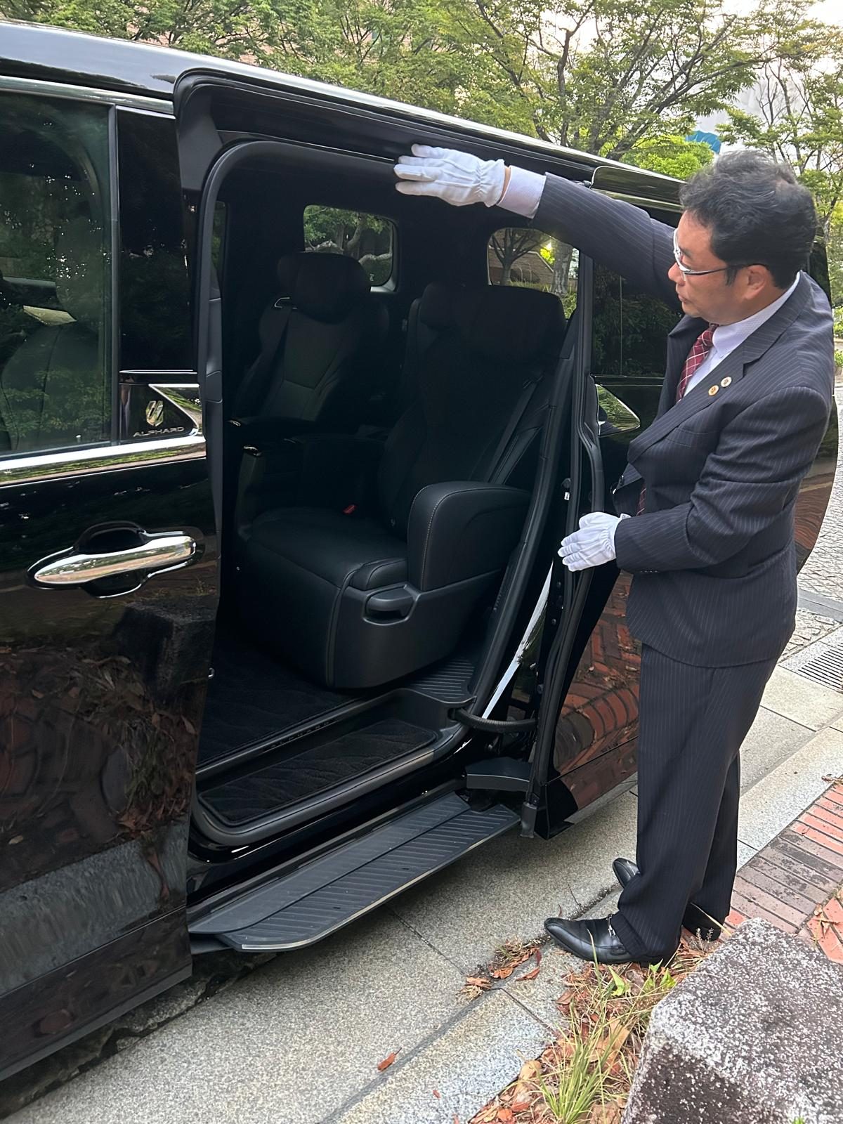 アルファードのドアを開けてお客様をお迎えする代表